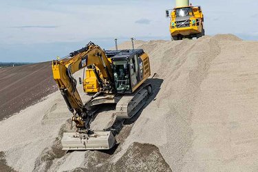 Deponiebau in München mit Geräten von Hagen Umwelttechnik vor Windrad